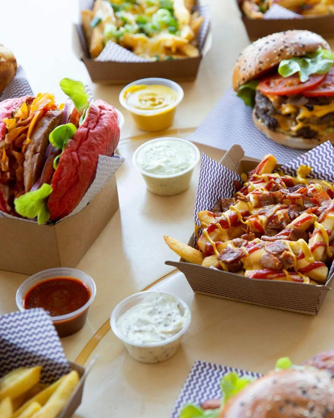 Burgers and loaded fries served in kraft food trays with sauce cups