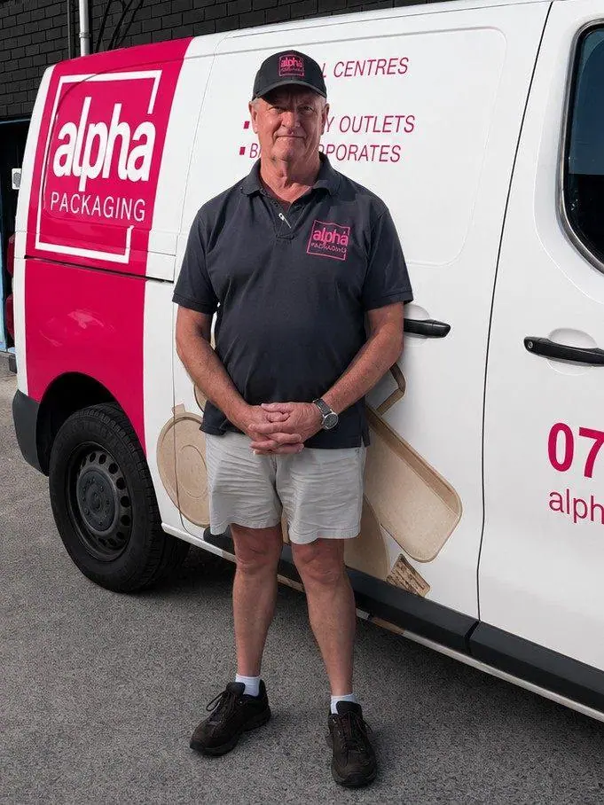 An Alpha Packaging driver beside a branded delivery van