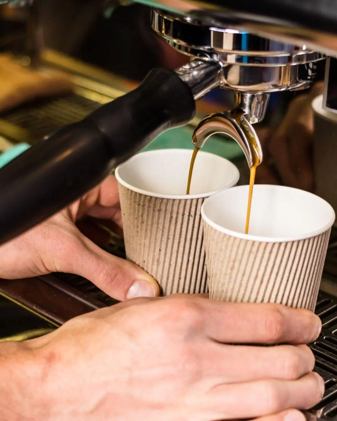 Espresso pouring into two ripple-wall takeaway coffee cups