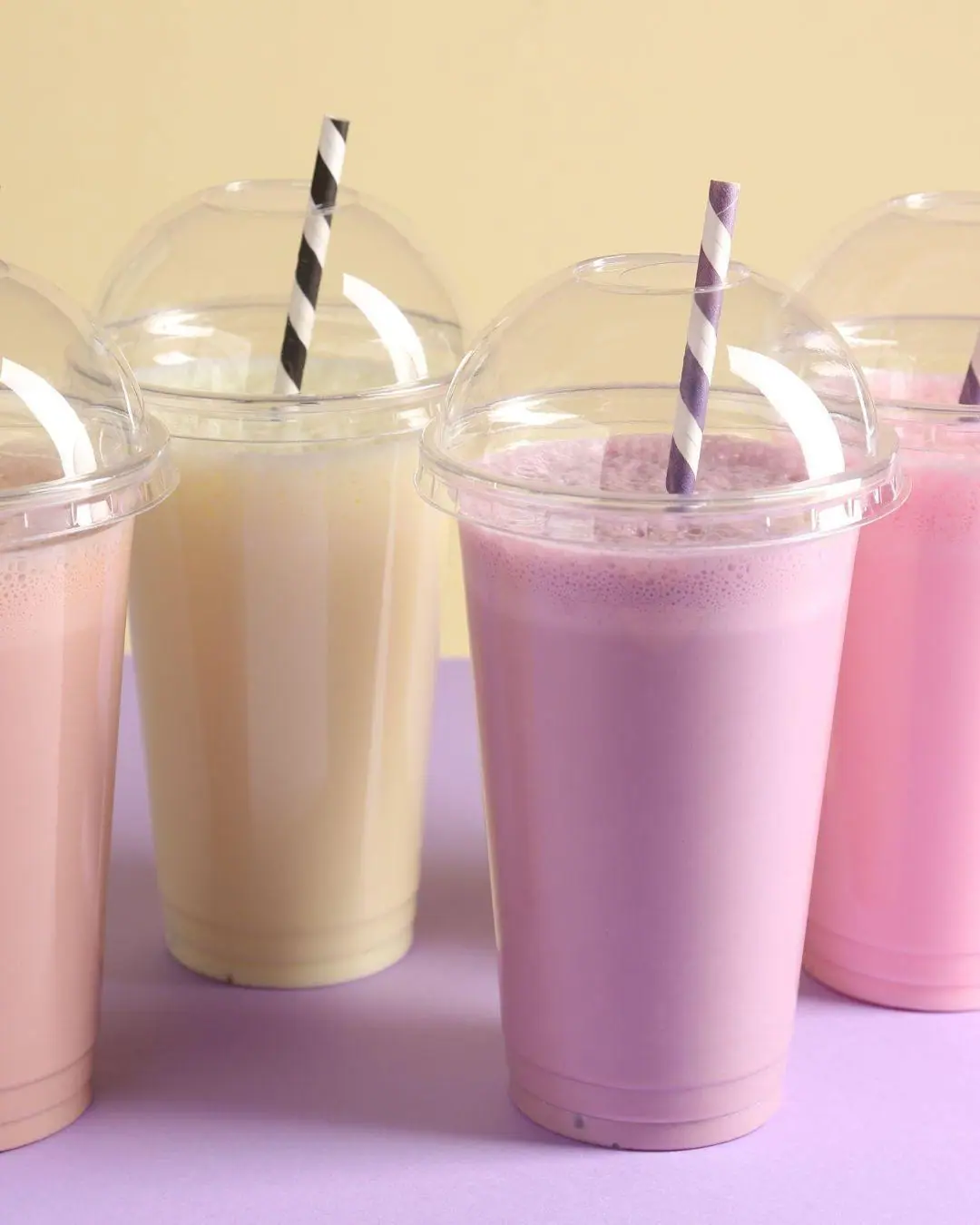 Pastel milkshakes in clear cups with dome lids and paper straws
