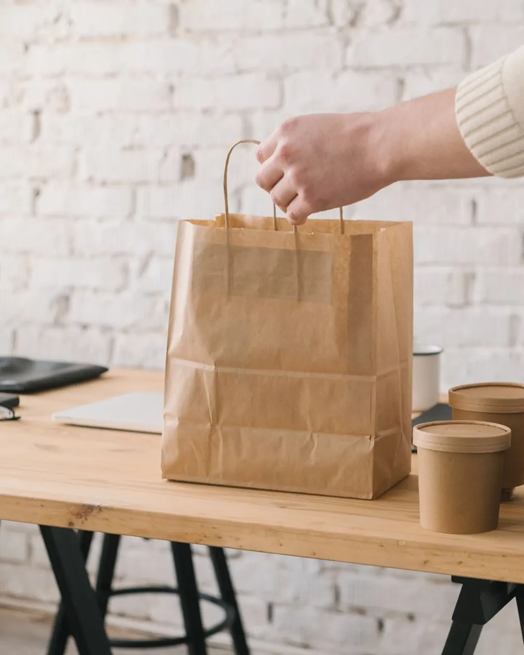 A kraft paper carry bag packed alongside takeaway containers