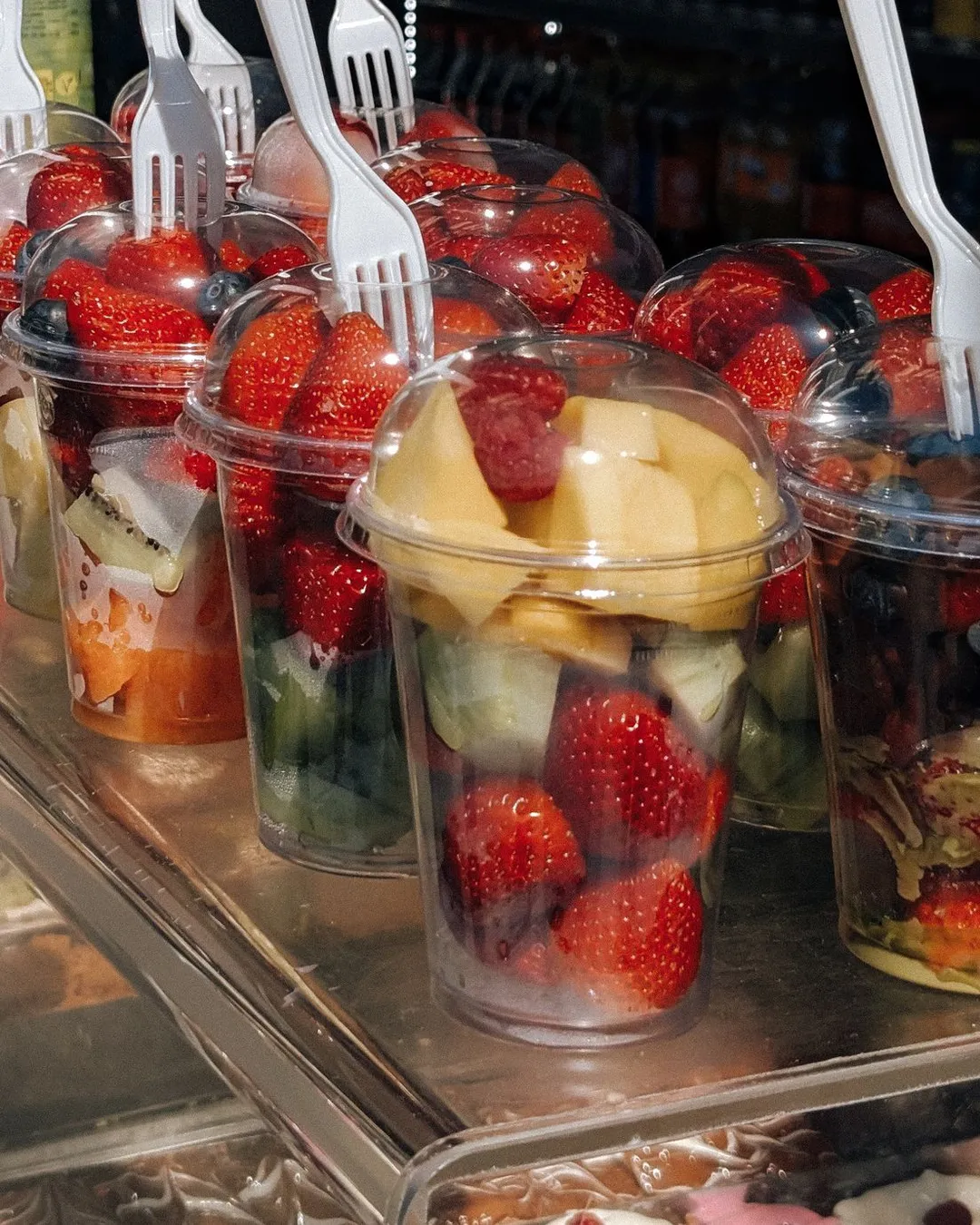 Fruit salads in clear cups with dome lids and disposable forks